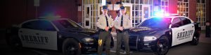 Photo of two Gilmertt County Sheriffs standing in front of their patrol cars